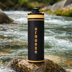 Urquelle Outdoor Filterflasche steht in einem Fluss mit Tropfen vom Wasserholen